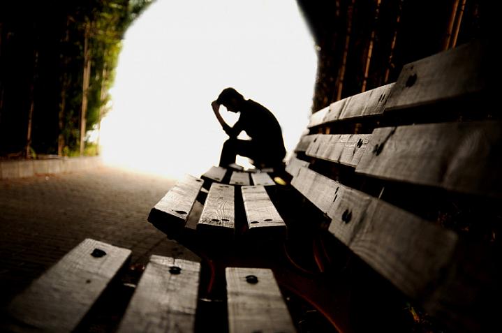 Person sitting alone on a bench in a tunnel Person sitting alone on a bench in a tunnel.