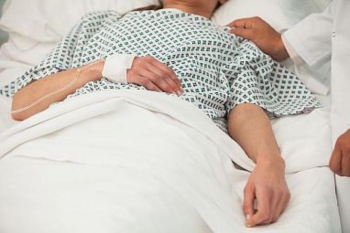 Heath care worker placing a hand on the shoulder of a sick patient in bed Heath care worker placing a hand on the shoulder of a sick patient in bed.