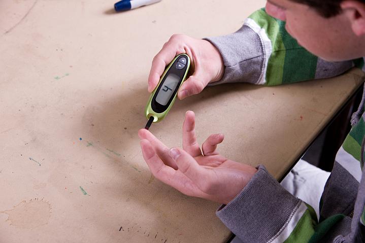 Teen boy checking blood sugar.