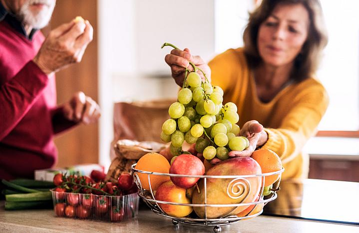 Woman choosing grapes from a basket of fruit Woman choosing grapes from a basket of fruit