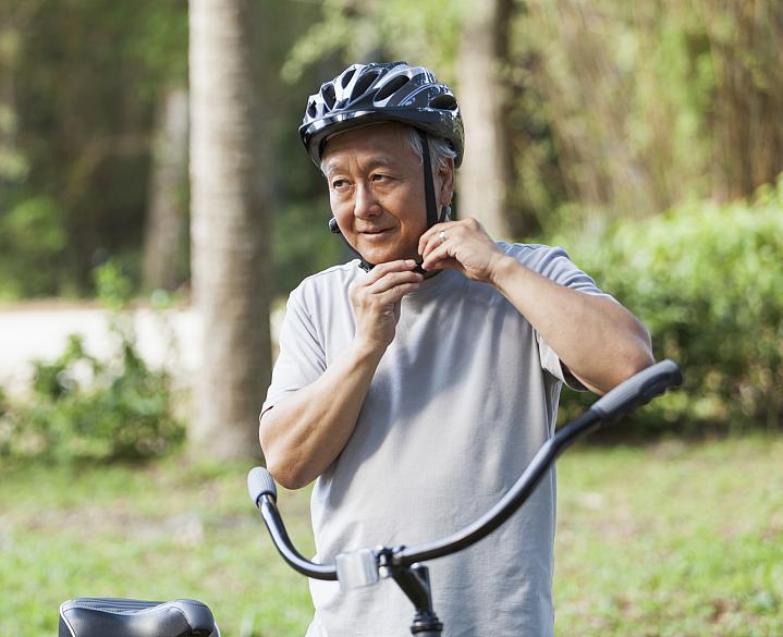Older man buckling his bike helmet Older man buckling his bike helmet