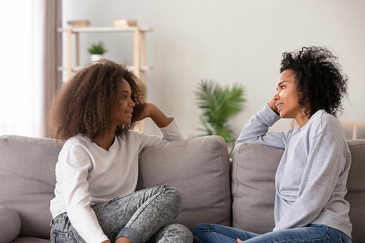 Mom listening to her teenage daughter while sitting on the couch together