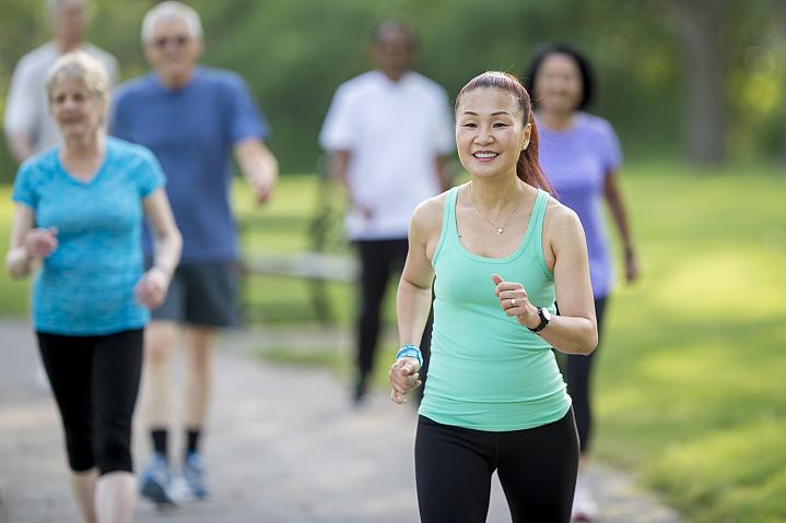 Group of older adults walking in a park on a sunny day